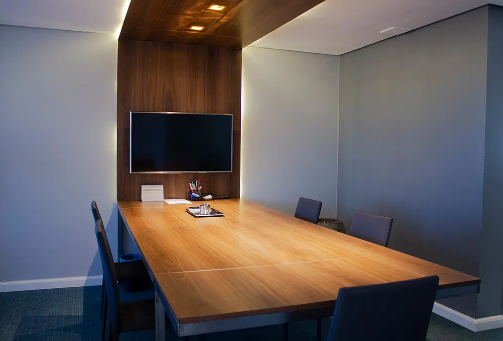 A sala de reunião da Macaw: uma enorme mesa com cadeiras ao redor e um monitor grande na parede da ponta.